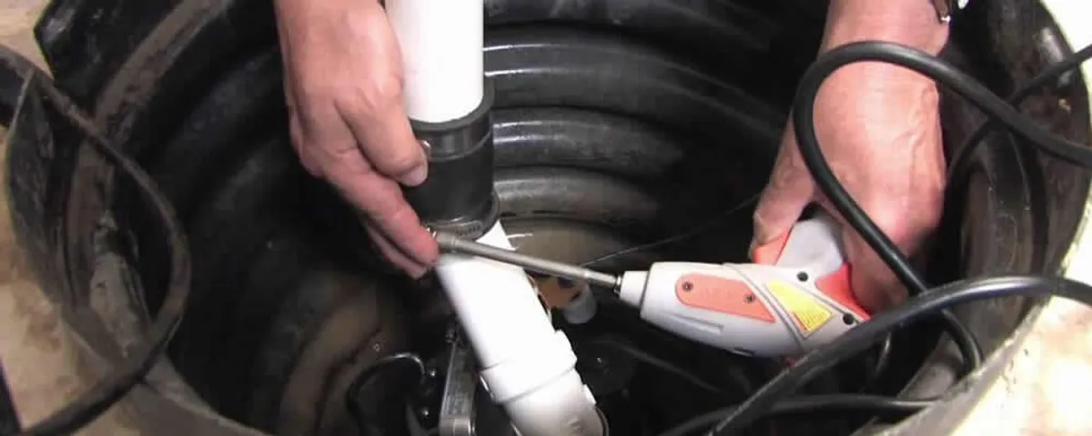 Sump pump installation technician connecting PVC discharge piping in Aurora, CO